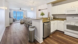 A modern kitchen with white cabinets, a granite countertop, stainless steel appliances, and a view to the outside.