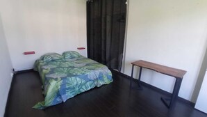 A small, dimly lit room with a bed, a bench, and a curtain. - Seasonal Rental, Duplex (Saint-Denis)
