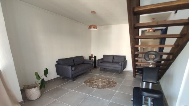 A living room with two grey sofas, a patterned rug, a small plant, and a pull-up bar. - Seasonal Rental, Duplex (Saint-Denis)