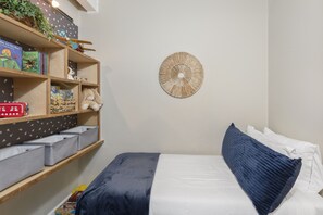 A bedroom with a bed, a bookshelf, and a wall decoration.
