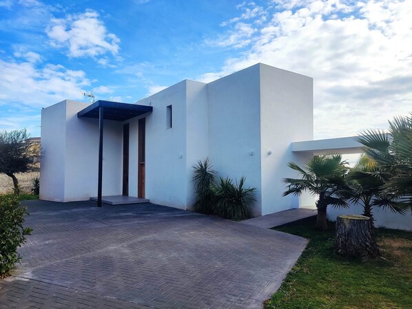 A modern building with a flat roof, a covered entrance, and a paved driveway. - VILLA EULALIA, LUXURY ON THE FIRST LINE OF THE SEA (Vinaròs)