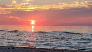 Atardecer sobre un mar tranquilo con una playa en primer plano.