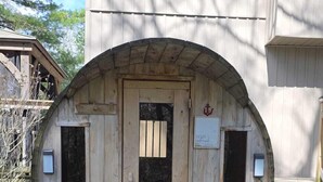Una estructura de barril de madera con puerta, ventanas y un letrero.