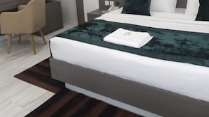 A modern hotel room with a large bed, a desk, and a chair. - City Green Hotel Yola (Jimeta)