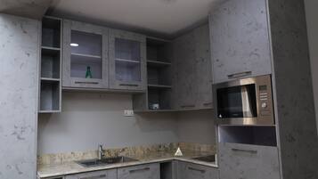 Een keuken met grijze kastjes, een roestvrijstalen magnetron en een granieten aanrecht.
