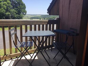 A small outdoor patio with a table and chairs, overlooking a scenic landscape.