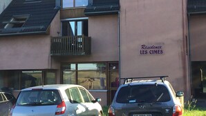 A building with a sign reading "Residence LES CIVES" and two parked cars in front. - APPARTEMENT VACANCES LAGUIOLE (Laguiole)