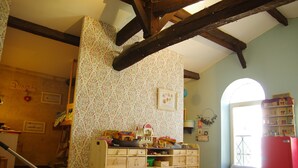 Um quarto com berço de madeira, área de recreação com brinquedos e um trem de brinquedo vermelho.