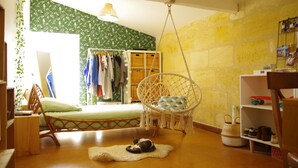 Um quarto com cama, uma cadeira suspensa, um guarda-roupa e um sapateiro.