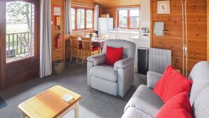 Interior d'una cabana acollidora amb zona de menjador, petita cuina i espai d'estar.