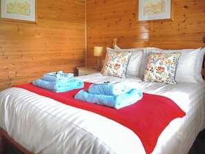 A wooden-paneled room with a bed, pillows, and a nightstand. - Spacious lodge in peaceful countryside, enjoying lovely views. (Nawton, near Helmsley)