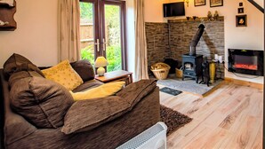 Ein gemütliches Wohnzimmer mit einer Couch, einem Kamin, einem Fernseher und einer Steinwand.