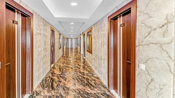 Un couloir doté de sols en marbre et de portes en bois, numérotées 201 et 209.