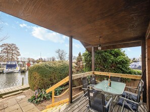 A covered outdoor seating area with a view of a canal and boats.