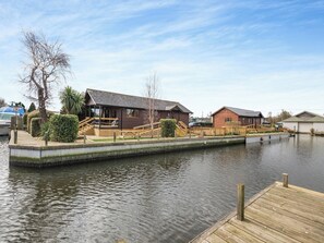 A riverside property with a dock, wooden buildings, and a boat docked nearby.