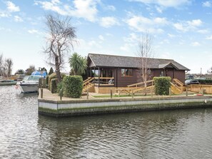 A riverside building with a dock, a staircase, and a small deck area. - Perfect riverside holiday accommodation, set on the water’s edge at Brundall. (Brundall)