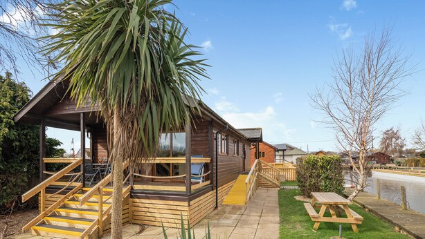 A wooden cabin with a staircase, a patio, and a view of the water.