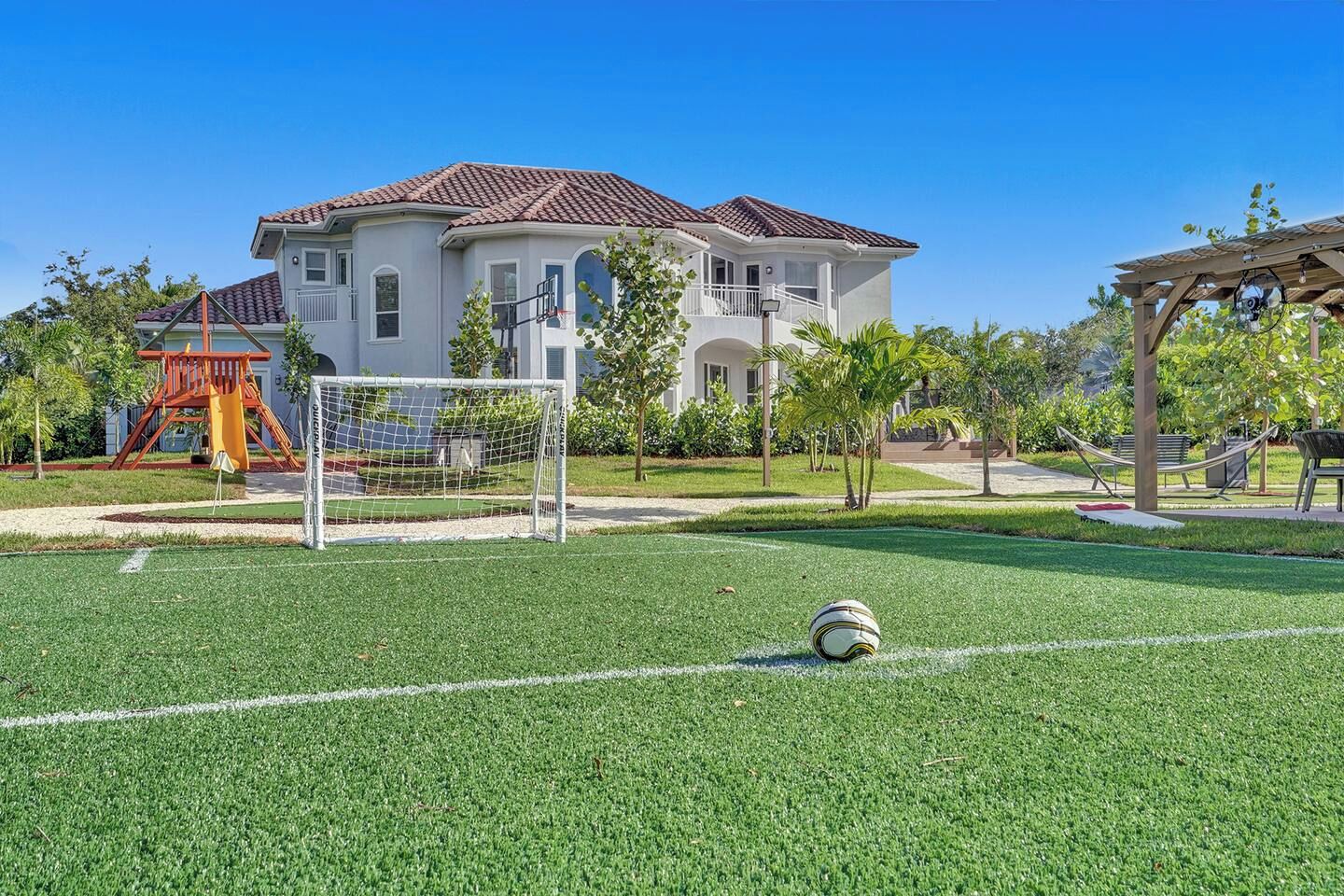 A soccer field with a goalpost, a hammock, and a playground structure.