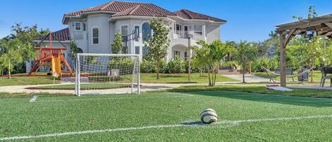 A soccer field with a goalpost, a hammock, and a playground structure.