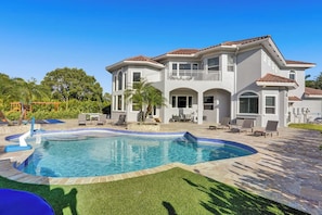 Une maison à deux étages avec une piscine, du mobilier d’extérieur et une pelouse bien entretenue.