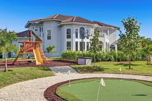Une grande maison avec un court de tennis et une aire de jeux.
