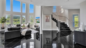 A spacious living room with a modern staircase, large windows, and a minimalist design. - Lavish 8 Br Estate with Pool & Courts (Plantation)