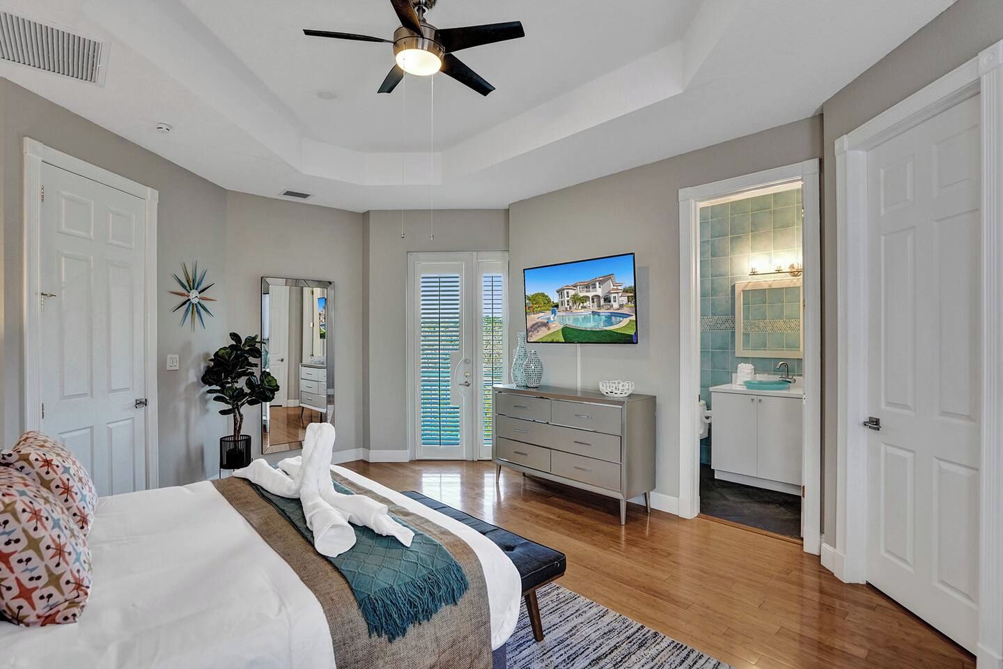 A bedroom with a bed, a dresser, a television, and a bathroom with a sink and mirror.