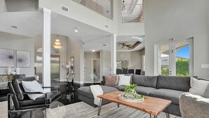A spacious living room with a gray sectional sofa, a wooden coffee table, and a black leather couch. - Lavish 8 Br Estate with Pool & Courts (Plantation)