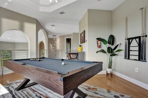 A pool table in a room with a staircase, a plant, and a window with blinds. - Lavish 8 Br Estate with Pool & Courts (Plantation)