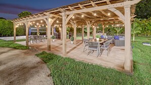 An outdoor patio with a pergola structure, outdoor seating, and a barbecue area. - Lavish 8 Br Estate with Pool & Courts (Plantation)