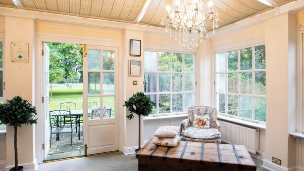 Een kamer met een houten bank, een bloemenstoel en een kroonluchter.