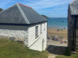 Un bâtiment situé sur la côte, doté d’un toit en pente, avec une plage en arrière-plan et une vue dégagée sur la mer.