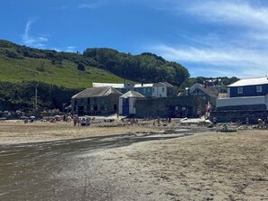 Une zone côtière avec des bâtiments, une plage et une colline en arrière-plan.
