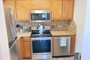 A kitchen with wooden cabinets, stainless steel appliances including a microwave, stove, and dishwasher, and a granite countertop. - 2 bed 1 bath, 5 min to downtown, 12 min to base (Columbus)