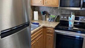 Une cuisine avec des meubles en bois, des appareils électroménagers en acier inoxydable et un tapis à motifs.