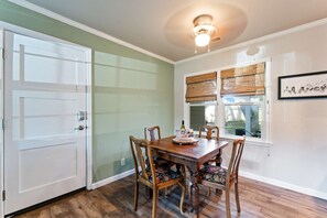 A dining area with a wooden table and chairs, a window with blinds, and a ceiling light fixture. - Reno Roost a welcoming private home with yard in Old SW Reno (Reno)