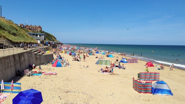 A beach with tents, umbrellas, and people. - Watchkeeper's Cottage (Mundesley)
