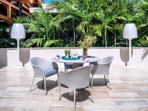 A round table with four chairs, surrounded by lush tropical plants, with two tall floor lamps on either side. - Luxury Villa 8 Bedroom in Tortuga Bay Punta Cana (Punta Cana)