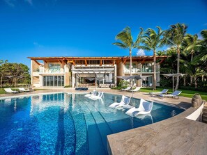 A modern resort with a large pool, lounge chairs, and palm trees. - Luxury Villa 8 Bedroom in Tortuga Bay Punta Cana (Punta Cana)