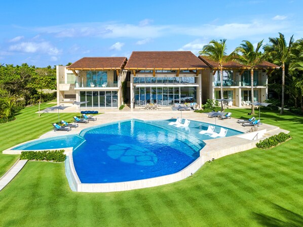 A modern resort with a large swimming pool, outdoor seating, and lush landscaping. - Luxury Villa 8 Bedroom in Tortuga Bay Punta Cana (Punta Cana)
