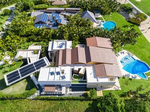 A modern house with solar panels, a swimming pool, and lush greenery. - Luxury Villa 8 Bedroom in Tortuga Bay Punta Cana (Punta Cana)