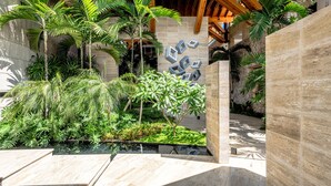 Een modern gebouw met een houten dak, stenen muren en diverse tropische planten.