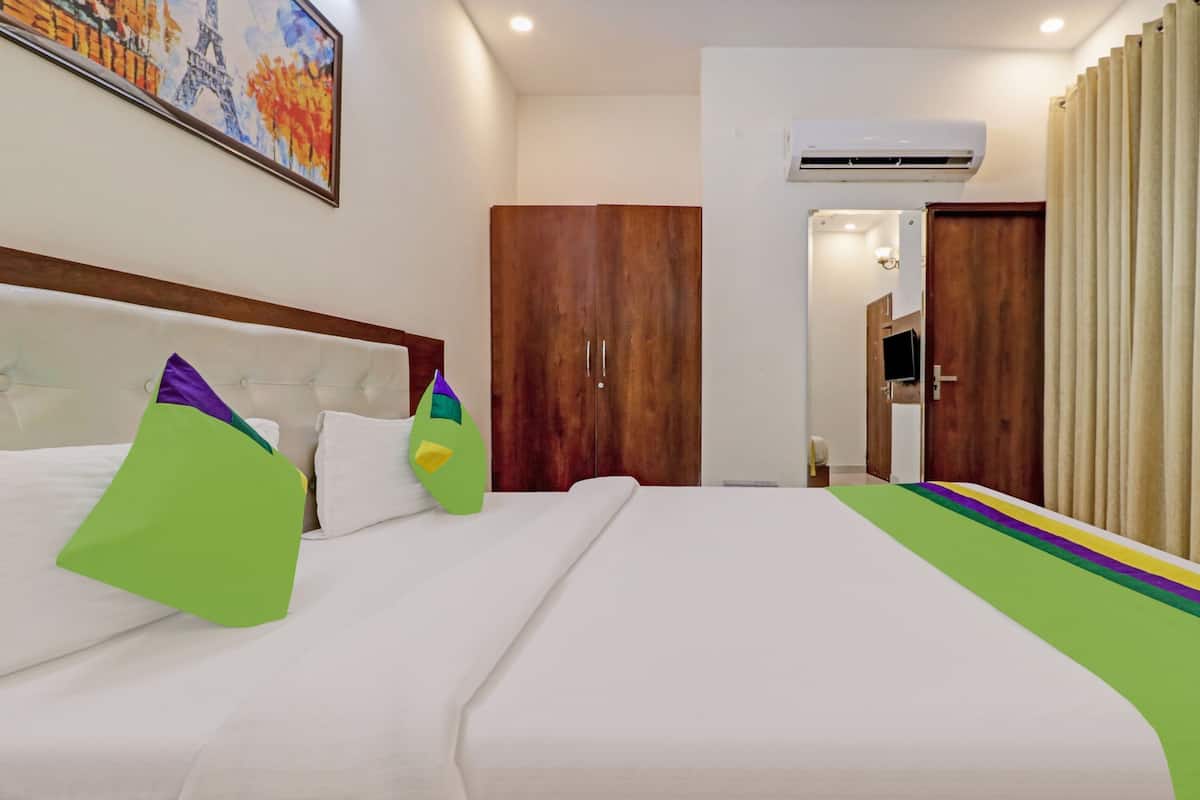 A hotel room with a bed, a wardrobe, an air conditioning unit, and a painting on the wall.