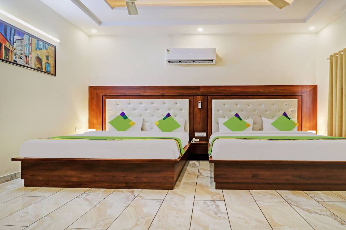 A hotel room with two beds, a wooden headboard, a painting on the wall, and a ceiling fan.