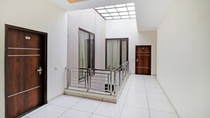A hallway with two wooden doors, a glass balcony, and a skylight. - Treebo Magnum Chandigarh (Mohali)