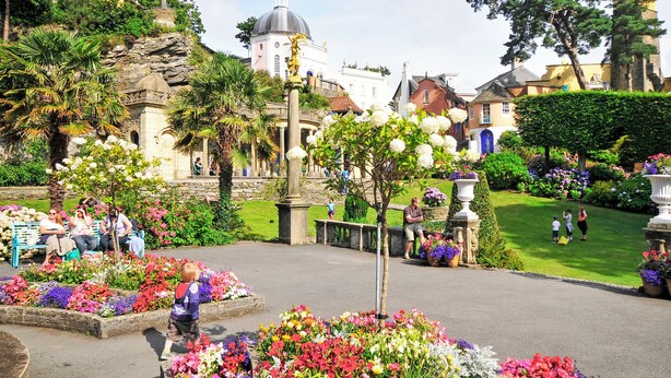 Ein Garten mit einem Brunnen, Bänken und verschiedenen Blumen.