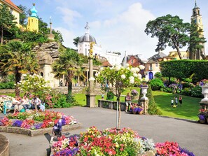 A garden with a fountain, benches, and a variety of flowers.