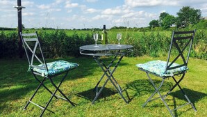An outdoor seating area with two chairs and a table, a birdhouse, and a grassy field in the background. - 2 bedroom accommodation in Caythorpe, near Nottingham (Caythorpe, near Nottingham)