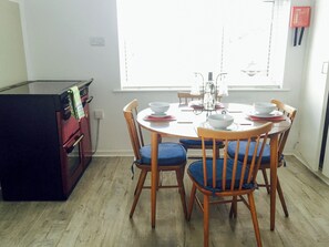 Un comedor con una mesa redonda, sillas y un refrigerador.