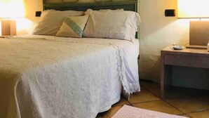 Ein Schlafzimmer mit einem Bett, zwei Nachttischen, einem Beistelltisch, einer Wanddekoration und einem Teppich.